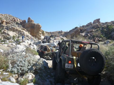 1997 Ford Ranger - Several Jeep Wranglers navigate a challenging rocky off-road trail under a clear blue sky.