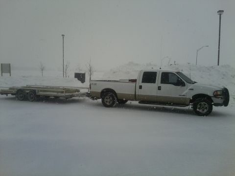 2000 Ford F-250 - A white and tan 2000 Ford F-250 truck is seen towing a trailer while parked in a snowy environment.