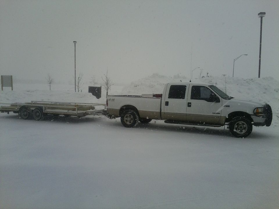 White and tan 2000 Ford F-250 towing a trailer in a snowy landscape