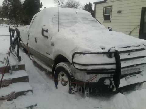 2000 Ford F-250 - A 2000 Ford F-250 truck is heavily covered in snow, with icicles hanging from the front bumper.