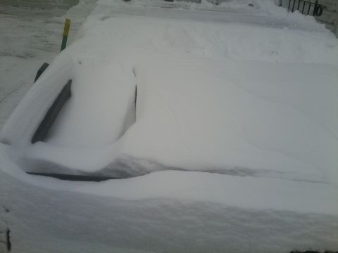 2000 Ford F-250 - A truck is heavily covered in snow, making identification of its make, model, or year impossible from this view.