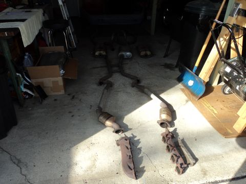 2004 Mercury Grand Marquis - Various exhaust system components laid out on a garage floor.