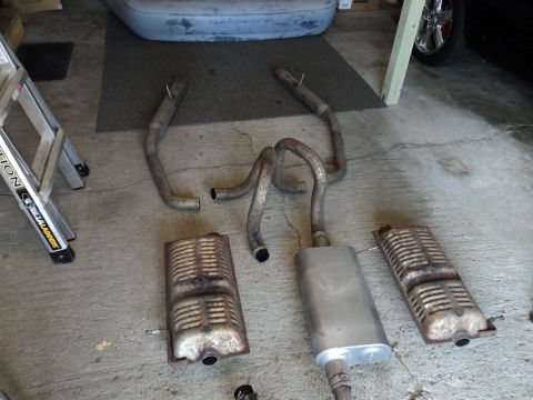 2004 Mercury Grand Marquis - Several exhaust system components are visible, including pipes and mufflers, on a garage floor.