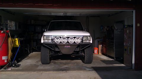 1996 Ford Bronco - A white 1996 Ford Bronco is parked inside a garage, equipped with a custom bumper and auxiliary lights.