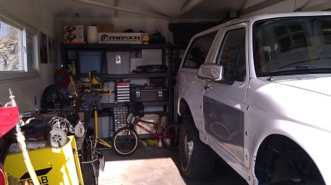 1996 Ford Bronco - A white 1996 Ford Bronco is parked inside a cluttered garage.