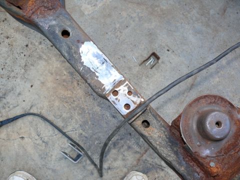 1976 Chevrolet Corvette - A close-up view of a heavily rusted vehicle frame section with a patch and wiring.