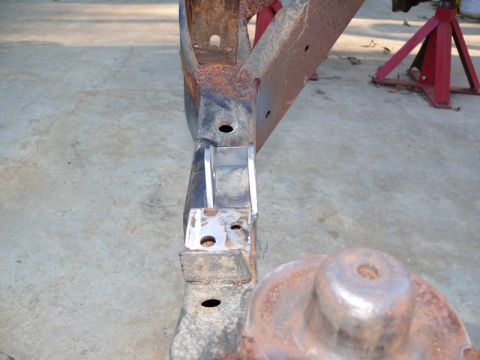 1976 Chevrolet Corvette - A close-up view of a heavily rusted vehicle frame section with added metal brackets and a round component.