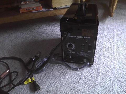 2003 Ford Crown Victoria - A black welding machine with various controls and attached cables is shown on a carpeted floor.