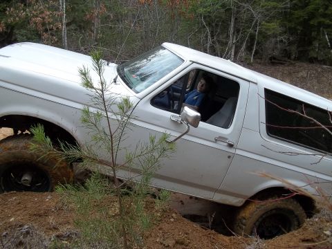 1990 Ford Bronco - This SUV appears to be stuck in a muddy ditch, with a person visible in the driver's seat.