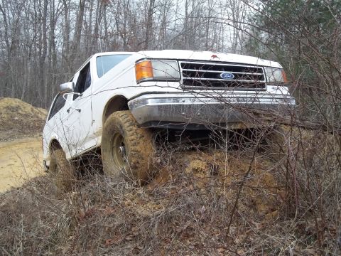 1990 Ford Bronco - White 1990 Ford Bronco navigating rough terrain off-road.