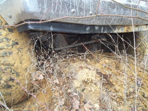 1990 Ford Bronco - The vehicle is stuck in the mud, with branches and debris covering the undercarriage.