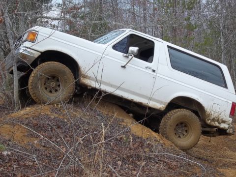 1990 Ford Bronco - This 1990 Ford Bronco is captured navigating a challenging off-road terrain, climbing a steep dirt incline.