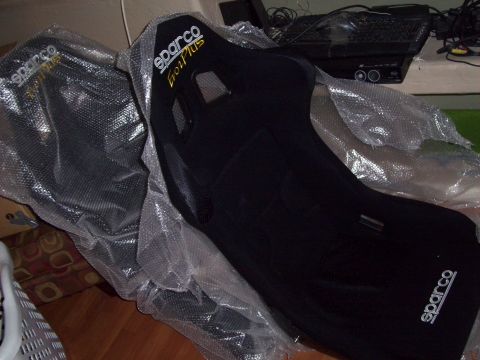 1995 Ford Probe - Two black Sparco racing seats, identified as Evo Plus models, are shown partially wrapped in protective plastic packaging.