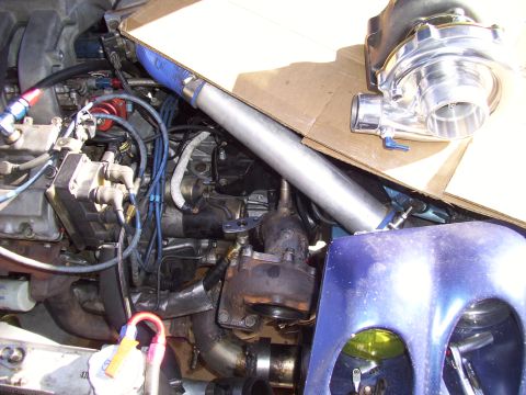1995 Ford Probe - Close-up of a modified engine bay a turbocharger and intercooler piping, with a blue fender visible.