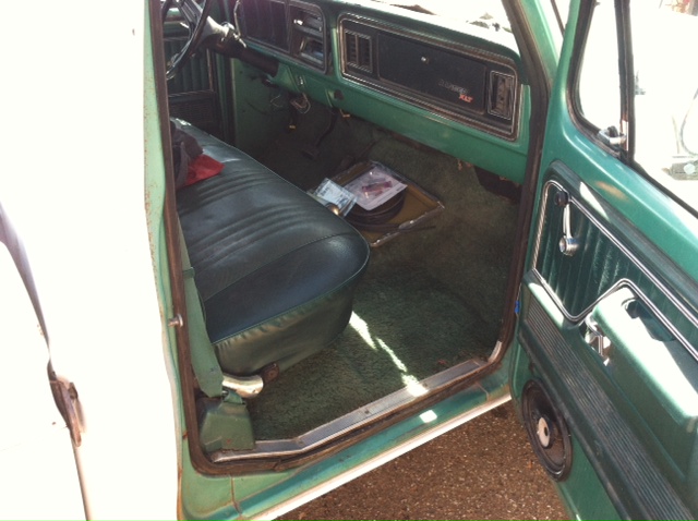 1977 Ford F-350 interior showing green dashboard, dark green bench seat, and door panel