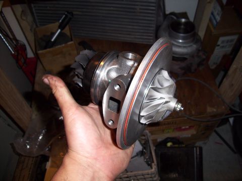 1995 Ford Probe - A turbocharger is held in a hand, with other automotive parts in the background.
