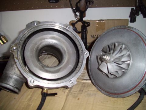 1995 Ford Probe - A disassembled turbocharger sits on a wooden surface, with its components laid out for inspection.