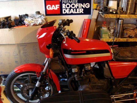 2008 Ford Crown Victoria - A red motorcycle with silver and black stripes on the tank is parked in a garage.
