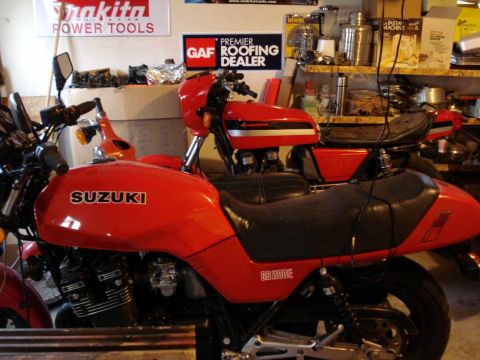 2008 Ford Crown Victoria - Two red motorcycles are parked in a garage, one in the foreground is a Suzuki GS1100E.