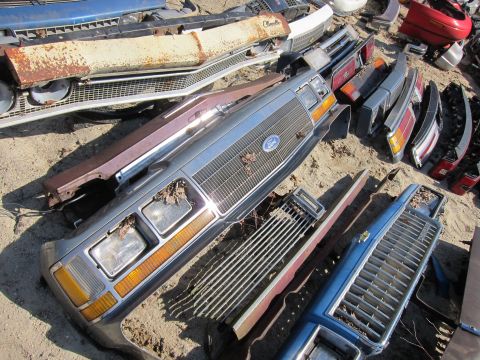 1991 Ford LTD Crown Victoria - A disassembled Ford Crown Victoria front end lies on the ground among other car parts.