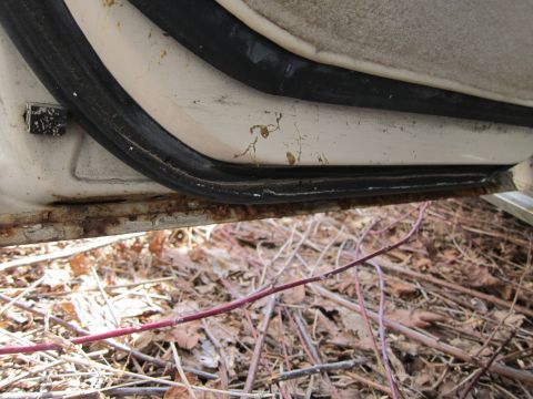 1991 Ford LTD Crown Victoria - Rust damage is visible on the door sill of a vehicle, with debris on the ground.