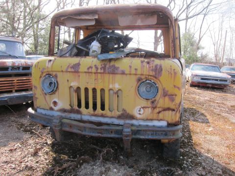 1991 Ford LTD Crown Victoria - This weathered Jeep truck sits in a junkyard, showing significant rust and missing parts.