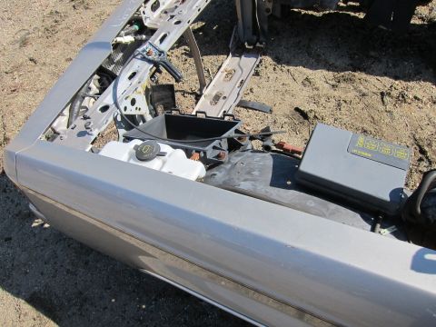 1991 Ford LTD Crown Victoria - Close-up of a silver car fender and exposed engine bay components, including a fuse box with visible text.