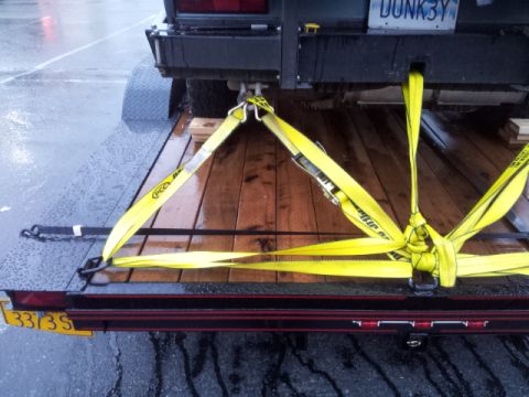2008 GMC Sierra 3500 - Yellow straps secure a vehicle to a trailer bed on a wet day.