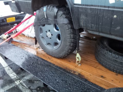 2008 GMC Sierra 3500 - A Volkswagen van is secured to a trailer with straps, showing its wheel and fender.
