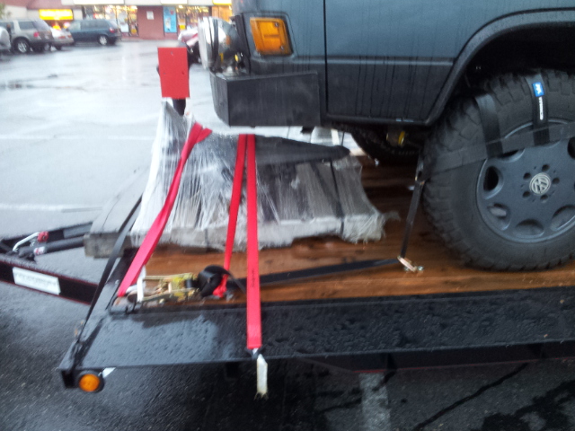 Trailer carrying a wrapped vehicle engine with red straps