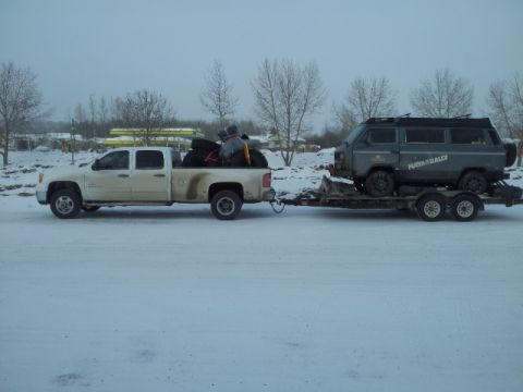 2008 GMC Sierra 3500 - A white 2008 GMC Sierra 3500 tows a van on a trailer through a snowy landscape.