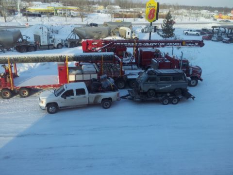 2008 GMC Sierra 3500 - A white GMC pickup truck tows a trailer carrying a gray van through a snowy landscape.