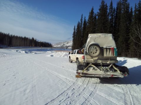 2008 GMC Sierra 3500 - A white pickup truck tows a white camper trailer through a snow-covered landscape.