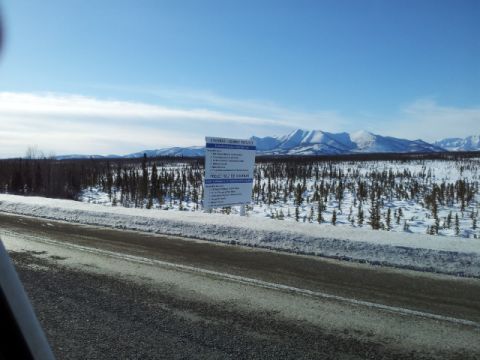 2008 GMC Sierra 3500 - A sign detailing project information stands in a winter landscape, with snow-covered trees and mountains in the background.