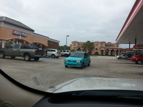 1991 Ford Festiva - A teal 1991 Ford Festiva is parked in front of a RaceTrac store.