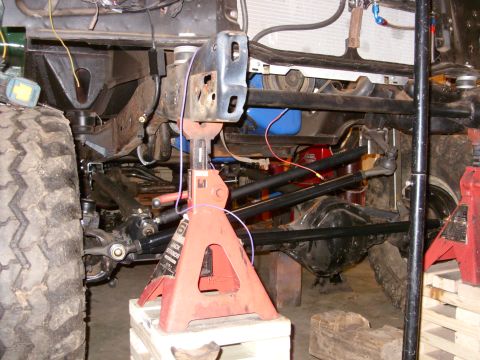 1967 Ford F-250 - Close-up view of a vehicle's front axle and suspension system, held up by jack stands.