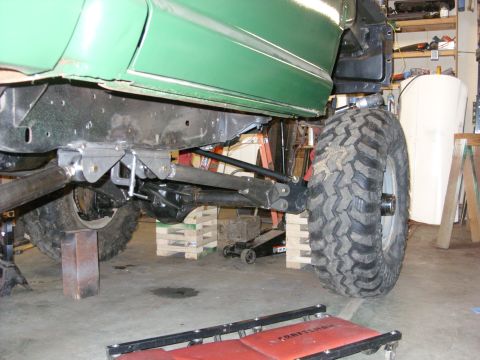 1967 Ford F-250 - The underside of a green truck shows its frame and suspension system, with large tires mounted.