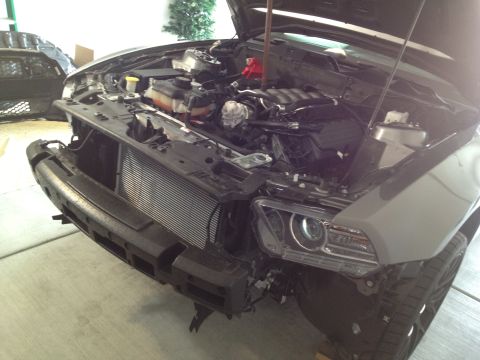 2013 Ford Mustang - The front of a gray Ford Mustang is shown with its hood open and bumper removed, revealing the engine and radiator.