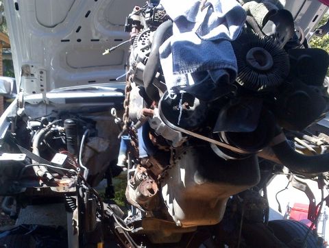 1994 Ford Bronco - Close-up view of a vehicle's engine assembly, with various components visible and some tools or rags placed on top.