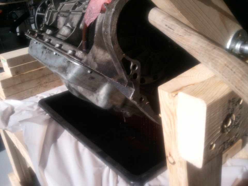 Transmission assembly draining into a pan, supported by wooden blocks