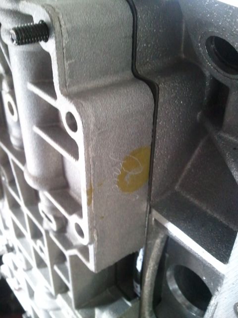 1994 Ford Bronco - A close-up view of a metal transmission component, possibly part of a Ford Bronco, shows a yellow marking on its surface.