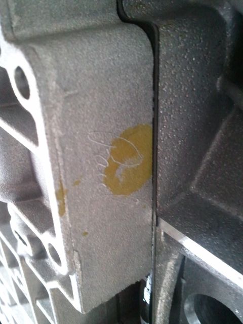 1994 Ford Bronco - Metal transmission housing part with a yellow mark and scribbled writing.