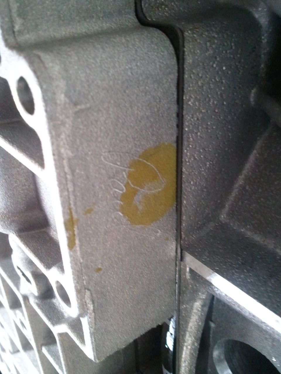 Close-up of a metal transmission housing with a yellow mark and some scribbled writing