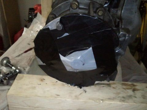 1994 Ford Bronco - A close-up view of a transmission housing partially covered with black tape, resting on a wooden surface.