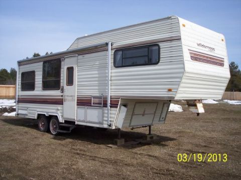 1973 Ford F-250 - This fifth wheel camper, branded 'Wilderness', is shown parked outdoors on a dry, grassy area.