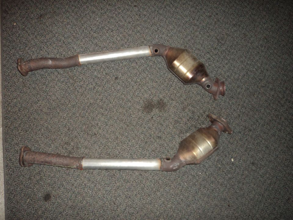 Two exhaust catalytic converters on a carpeted surface