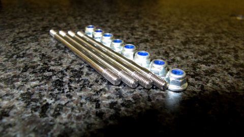1996 Ford Bronco - Engine studs and nuts laid out on a dark, speckled surface.