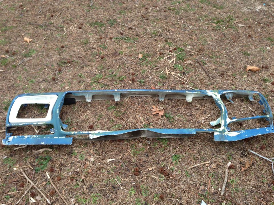 Blue painted front grille assembly with white trim, lying on the ground