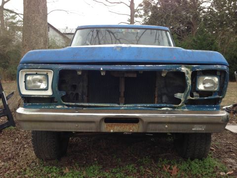 1979 Ford Bronco - This blue pickup truck is missing its grille and headlights, showing signs of wear and tear.