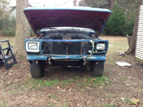 1979 Ford Bronco - This blue SUV, likely from the 1970s, sits with its hood open, revealing a damaged front end.
